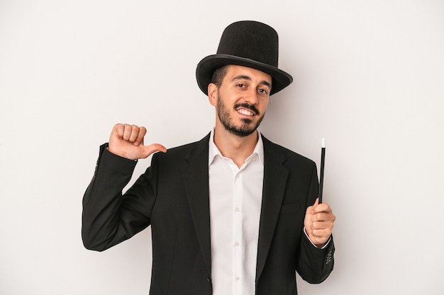 Young magician man holding wand isolated on white background feels proud and self confident, example to follow.