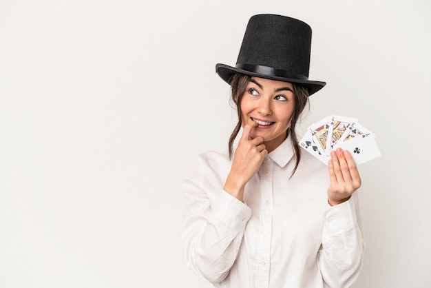 Young magician woman holding a wand isolated on white background relaxed thinking about something looking at a copy space