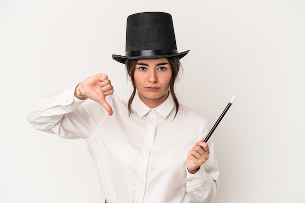 Young magician woman holding a wand isolated on white background showing a dislike gesture thumbs down Disagreement concept