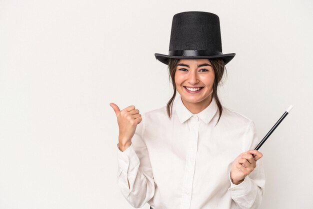 Young magician woman holding a wand isolated on white background smiling and raising thumb up