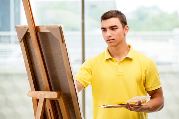 Young male artist drawing pictures in bright studio