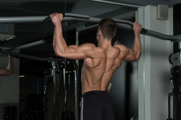 Giovane atleta maschio che fa pull up - chin-up in palestra