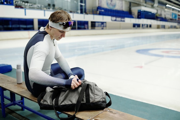 Young male athlete taking something in big grey sports bag