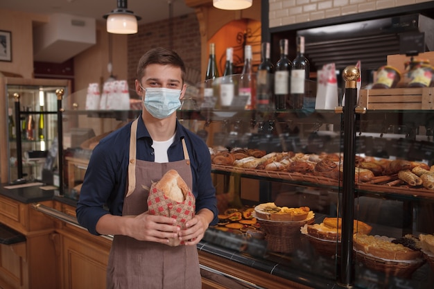 Photo young male baker wearing medical mask at work during coronavirus pandemic