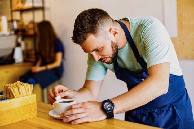 若い男性のバリスタがコーヒーを準備します