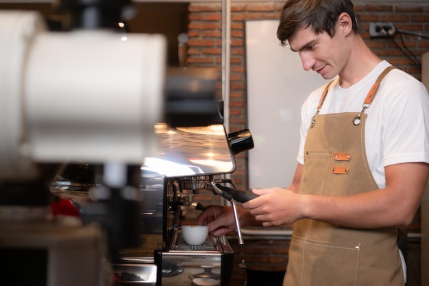 Young male barista preparing coffee in cafe Male barista using coffee machine