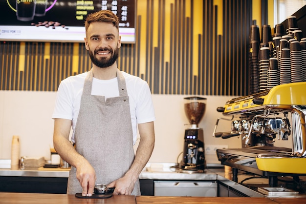 コーヒーショップでコーヒーを準備する若い男性のバリスタ