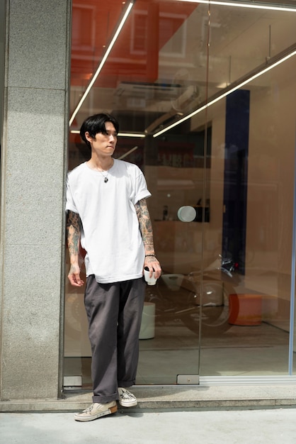 Young male barista with tattoos waiting outside the coffeehouse before opening