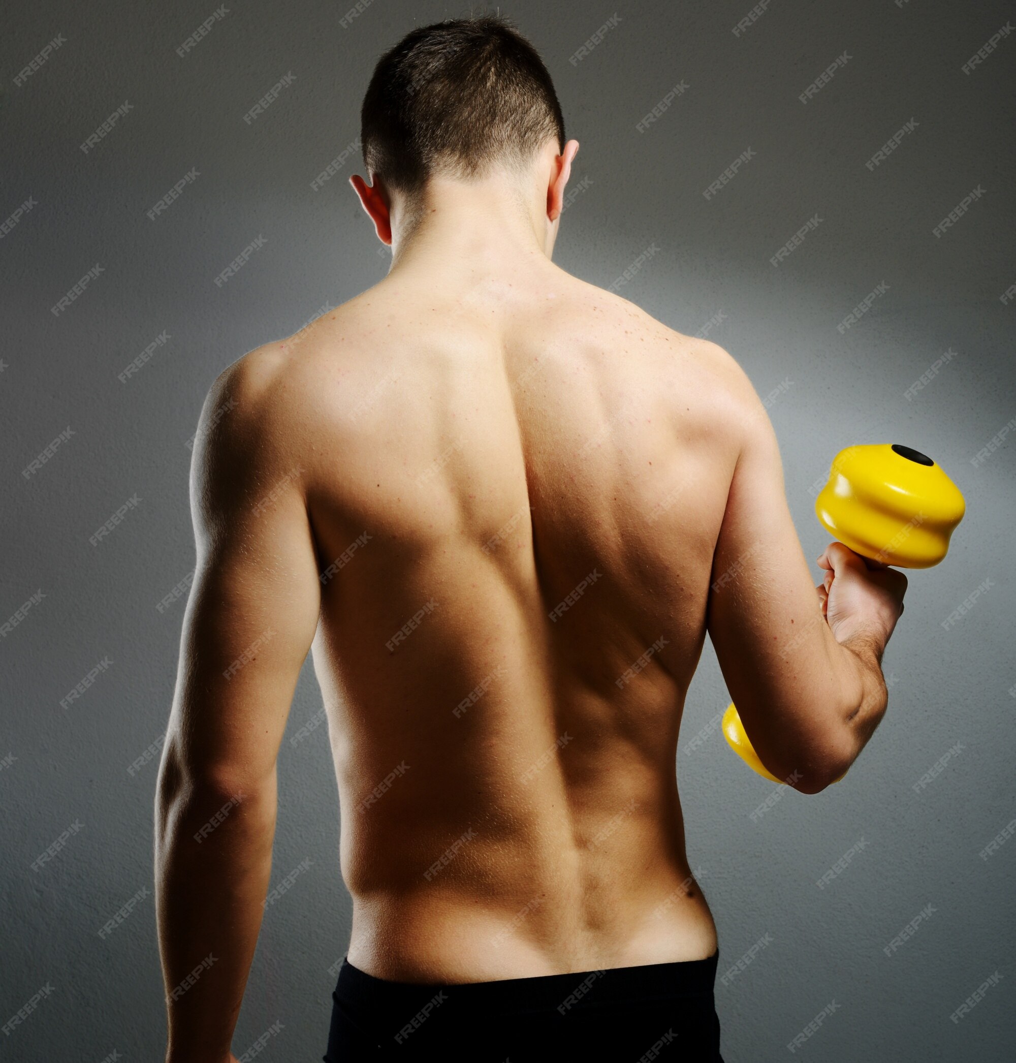 Premium Photo  Young male bodybuilder doing heavy weight exercise with  dumbbells against dark background