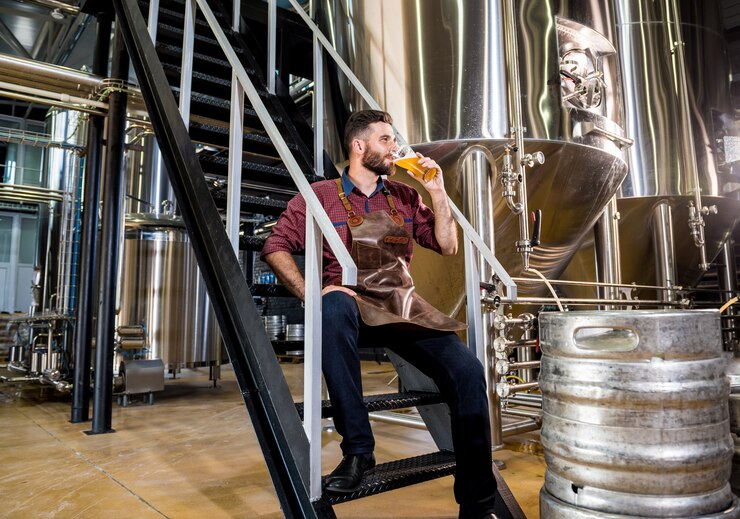 Photo young male brewer in leather apron at modern brewery factory