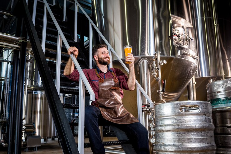 Photo young male brewer in leather apron at modern brewery factory