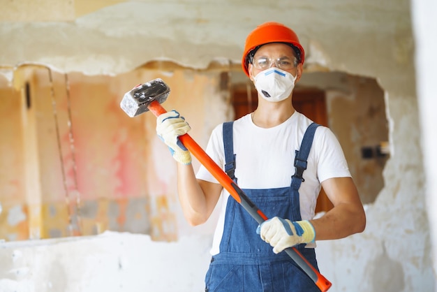 Young male builder in hard hat holding tools Apartment repair and renovation concept