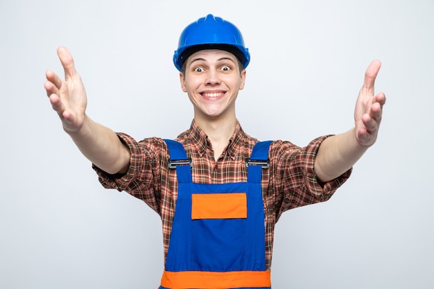 Young male builder wearing uniform isolated on white wall