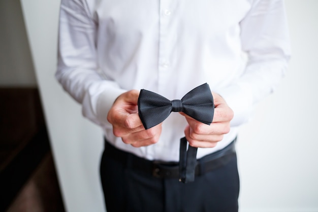 Young male businessman dressed in a white shirt with a short beard wears a black bow tie