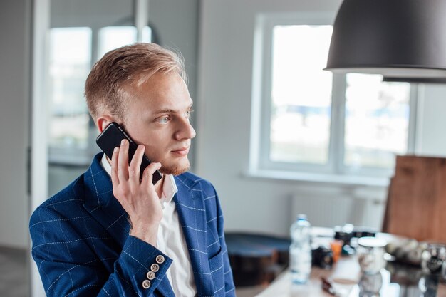 young male businessman speaks on the phone discussing a business project