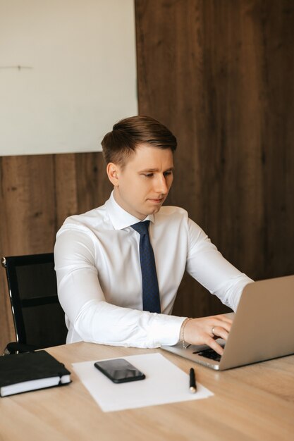 Young male businessman working on laptop in office.