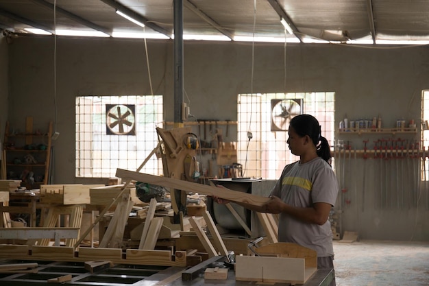 A young male carpenter and working overall equals a wooden bar with a mill machine