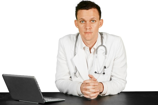 Young male caucasian doctor sitting at a desk and working on a laptop