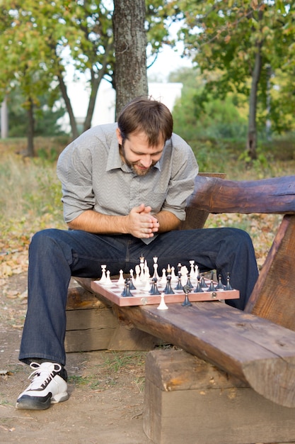 Premium Photo  Young bearded man in sunglasses sitting on a wooden park  bench planning his next chess move