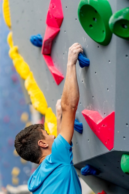 A young male climber practicing climbing on a climbing wall.