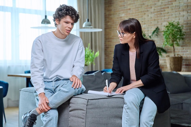 Young male communicates with female psychologist at therapy session in office