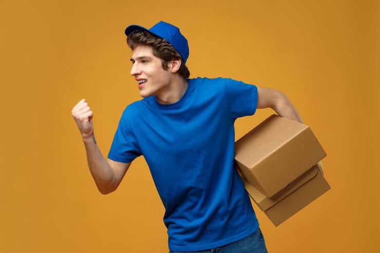Photo young male courier in a blue uniform holds parcel in his hands