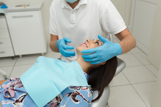 A young male dentist and happy female patient. Dentist office lifestyle scene. Doctor practice. Patient health care