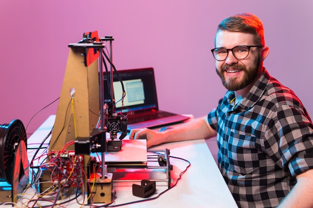 Young male designer engineer using a printer in the laboratory and studying a product prototype, technology and innovation concept.