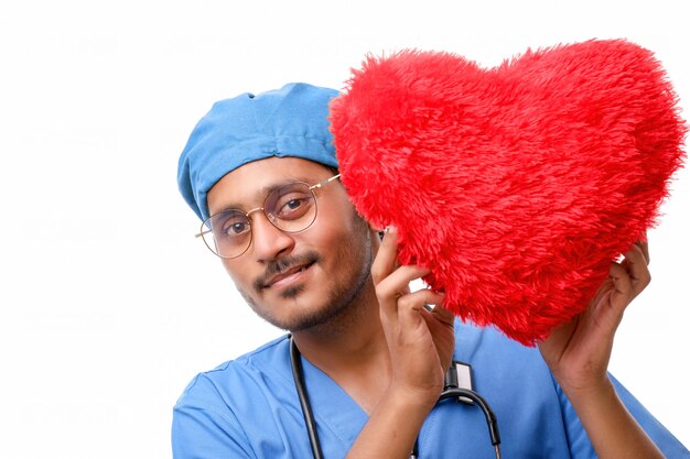 Young male doctor holding a beautiful red heart shape in hand