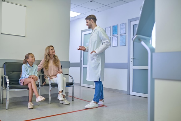 Young male doctor talking to the patients in the clinic hall