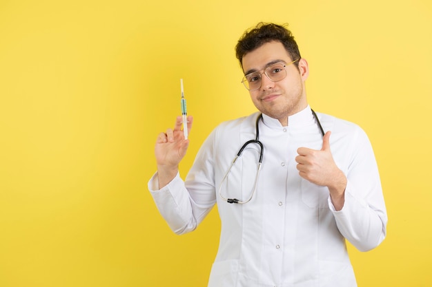 Young male doctor in white coat holding medical syringe. 