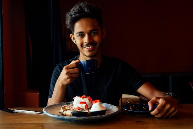 Young male drinking latte at coffee bar pancakes at cafe