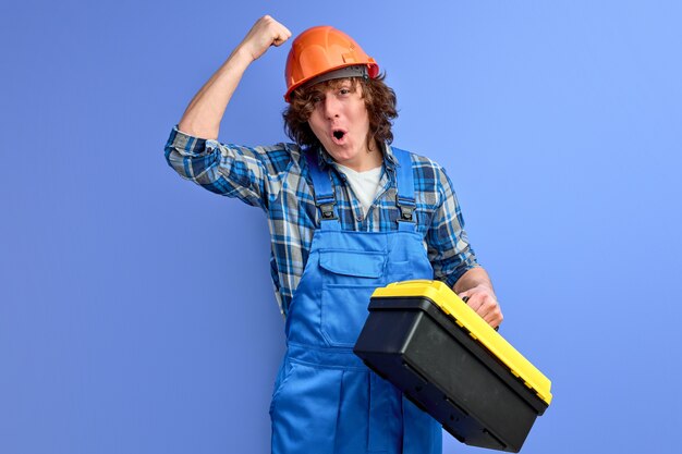 Young male engineer in blue overalls knocking on orange helmet, ensure employees working with good protection