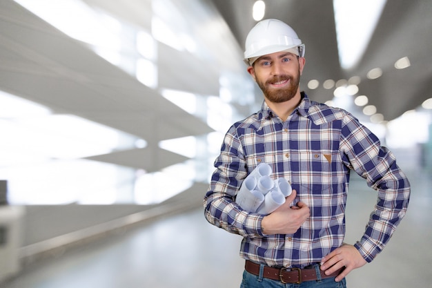 Young male engineer with helmet holding blueprints