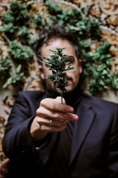 A young male executive surrounded by marijuana buds and calling for the legalization of cannabis