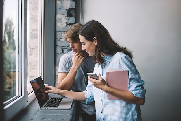 young male and female freelancers checking information on laptop computer during remote job indoors