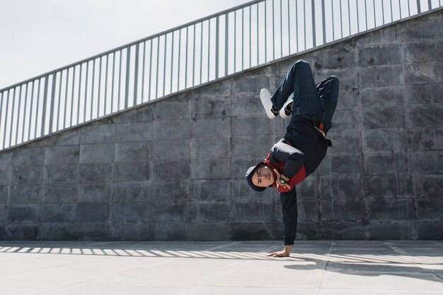 A young male in free acrobatic motion in the city street, beautiful physical sxercise