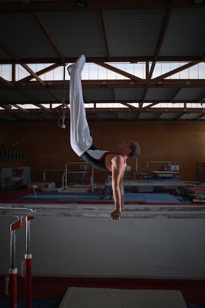 Young male gymnast doing exercises on the parallel apparatus.