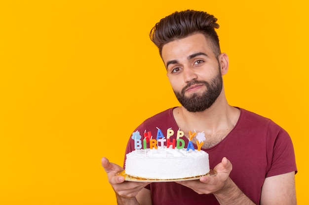 Giovane maschio hipster con la barba che tiene una torta con l'iscrizione congratulazioni di buon compleanno per l'anniversario e la vacanza. concetto di promozioni e sconti. copia spazio