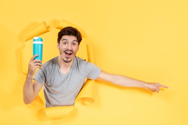 young male holding green bottle on yellow background athlete fit workout gym