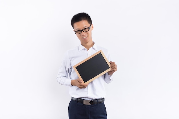 A young male holds a small blackboard in his hand