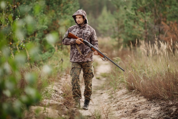 Young male hunter in camouflage clothes ready to hunt with hunting rifle