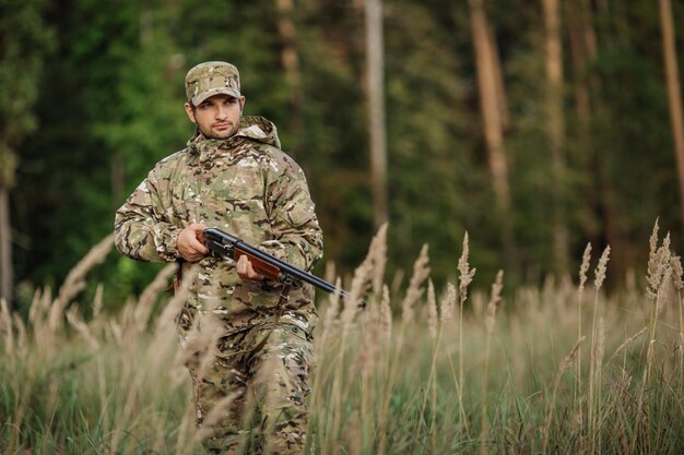 Young male hunter in camouflage clothes ready to hunt with hunting rifle