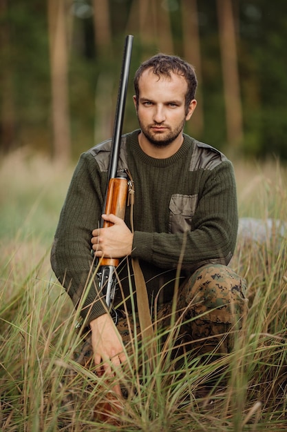 사냥용 소총으로 사냥할 준비가 된 위장 옷을 입은 젊은 남성 사냥꾼