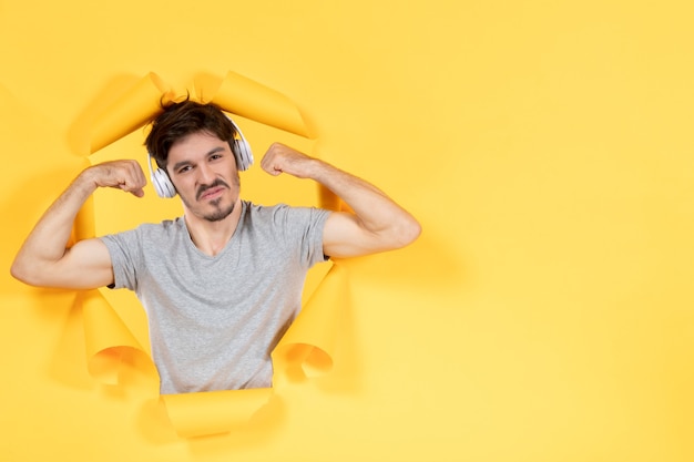 young male listening to music in headphones and flexing yellow paper background ultrasound audio