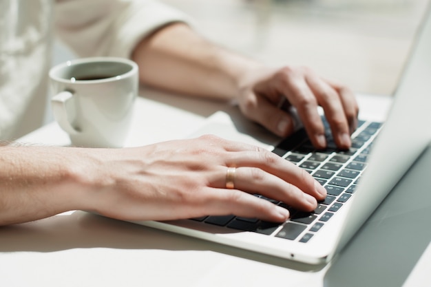 A young male millennial works remotely on a laptop. 