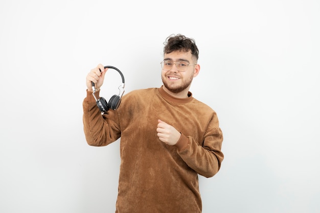 young male model holding black headphones.