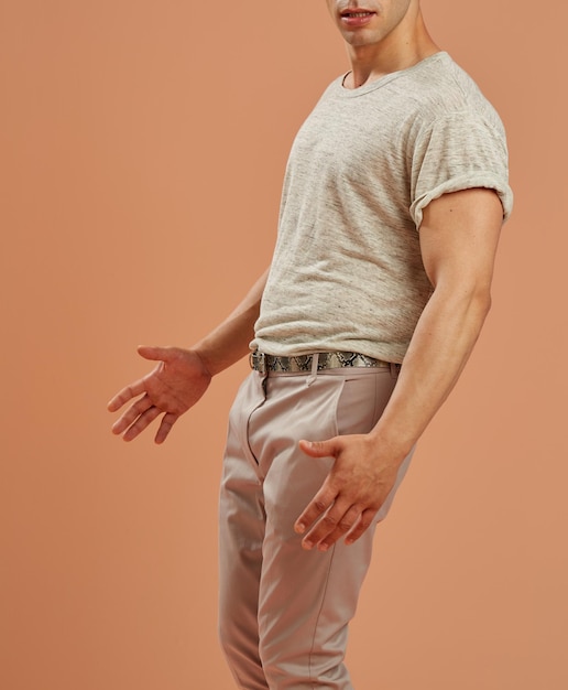 Молодой мужчина-модель в повседневной одежде медленно танцует на коричневом фоне