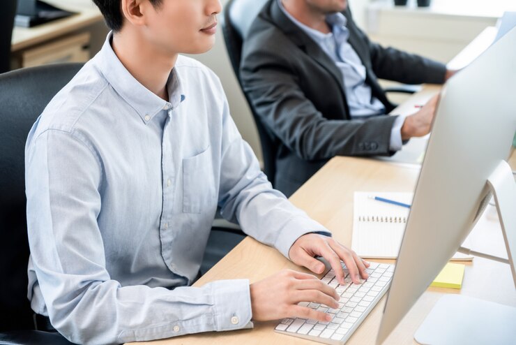 Photo コンピューターに取り組んでいる若い男性事務員