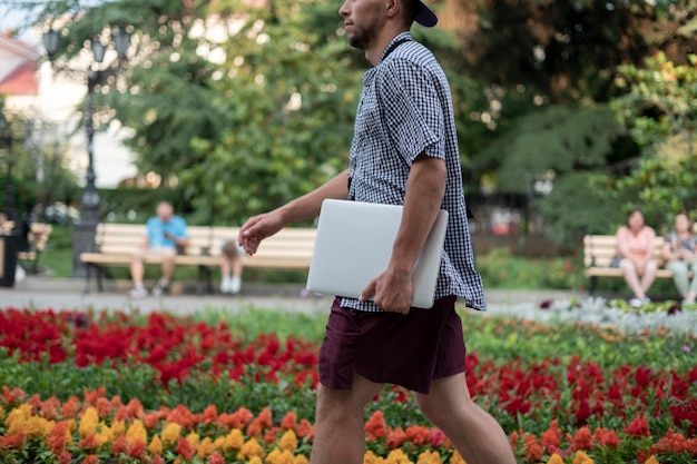 A young male person carrying the laptop in the city